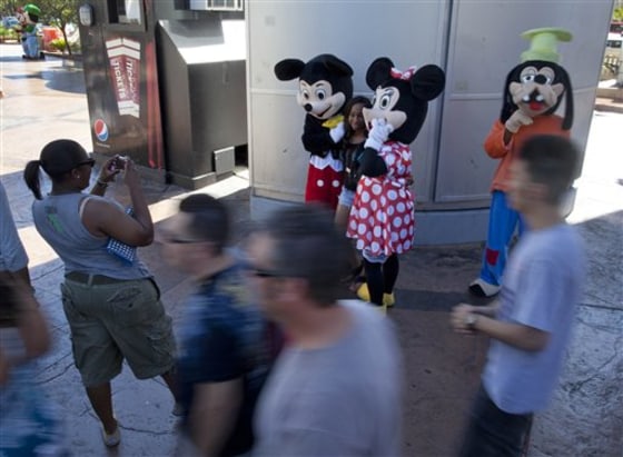 James Miller, left, and Robyn Vanderlip — dressed as Mickey and Minnie Mouse — pose with a tourist on The Strip on Saturday in Las Vegas.